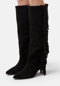 Stivali alti neri in suede con punta affusolata e tacco basso, caratterizzati da dettagli in frange laterali per un tocco di texture e interesse.
