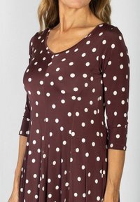 Brązowa sukienka w kropki, z krótkim rękawem, dekoltem w serek, wykonana z gładkiego materiału, z białymi kropkami, z rozkloszowanym dolnym częścią i detalami szwów.