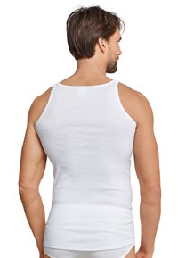 Hvid bomulds tanktop med et klassisk design, ærmeløs skæring og en glat tekstur, der viser bagsiden af bæreren.