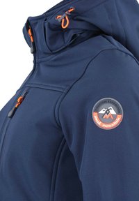 Marineblå softshell-jakke med orange detaljer, en lynlåshætte og et rundt "Mountain Expedition"-mærke på venstre skulder.