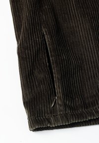 Ciemnozielona tkanina kordurowa z pionowym prążkowanym wzorem, z bocznym zamkiem błyskawicznym oraz miękkim, pluszowym wykończeniem u dołu.