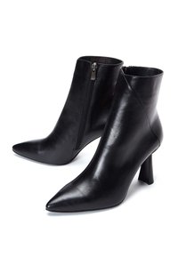 Bottes cheville en cuir noir avec bouts pointus, fermeture éclair latérale et talons effilés. Texture lisse avec un design élégant et minimaliste.