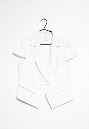Hvid blazer med korte ærmer, revers og dobbelt-knaplukning hængende på en sort bøjle mod en hvid baggrund.