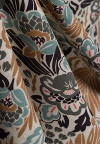 Blumenstoff mit einer Mischung aus Grün-, Türkis-, Braun- und Schwarztönen. Die Textur ist glatt mit einem baumwollartigen Aussehen und detaillierten Mustern.