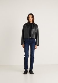 Fekete bőr, rövidített kabát gallérral, fekete felsővel, kék farmerrel és fekete cipővel párosítva. Egyszerű kialakítás és sima textúra.