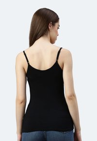 Schwarzes, eng anliegendes Tanktop mit Spaghettiträgern, aus einem glatten, dehnbaren Stoff gefertigt. Verfügt über ein abgerundetes Rückendesign und dezente Etikettendetails.