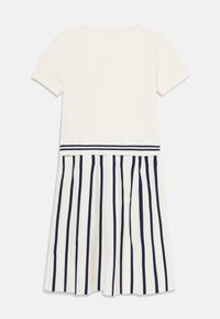 Dzianinowa sukienka z białą, fakturowaną górą i plisowaną spódnicą w pionowe granatowe paski. Krótkie rękawy oraz poziomy pasek w paski w talii.