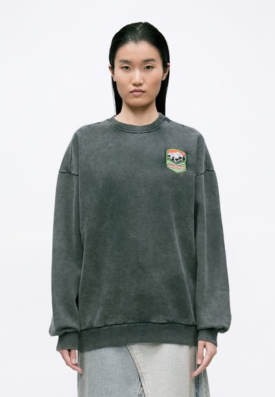 Hanorac gri cu guler rotund, umeri căzuți, mansete și tiv din tricot. Dispune de un logo colorat brodat pe piept.