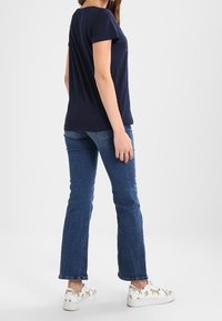 Camiseta de algodón de manga corta en azul marino combinada con jeans de mezclilla acampanados y zapatillas blancas con gráficos de animales.