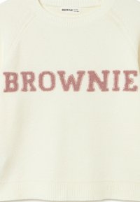 Suéter color crema con cuello y dobladillo acanalados. "BROWNIE" se muestra prominentemente en un bordado de suave color rosa en el centro.