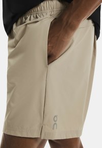 Gai beige šorti ar elastīgu jostasviedi, sānu kabatām un logotipa akcentu. Gluda tekstūra un atbrīvota piegriezuma dizains.