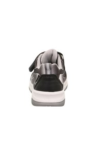 Schwarzer, grauer und weißer Sportschuh von hinten betrachtet, mit einem gepolsterten Kragen und einem Klettverschluss.