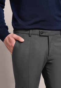Gray tailored pants with a smooth texture, featuring a button closure and belt loops. Paired with a navy blue knit sweater.