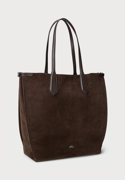 Sac tote en daim marron avec deux poignées en cuir marron, en forme rectangulaire, texture lisse et fermeture éclair. Présente un petit logo sur le devant.