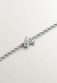 Pulsera de cadena de plata con un detalle central de lazo adornado con dos piedras preciosas transparentes. Textura suave y acabado pulido en toda la pieza.