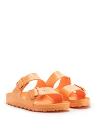 Sandalias naranjas hechas de un material suave y durable, con dos correas ajustables con hebillas y una suela texturizada para mayor agarre.