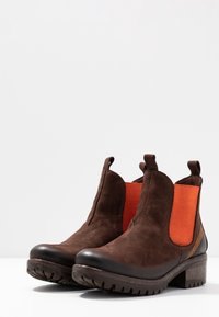 Ruske nubuk nilon saappaat oransseilla kankaalla sivuilla, joissa on pyöreä varvas ja teksturoitu kumipohja. Kerrostettu korko ja kontrastiväriset ompeleet.