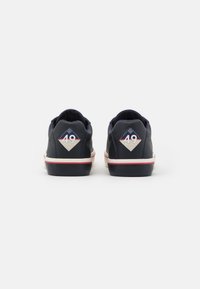 Marineblaue Sneaker mit einem obermaterial aus glattem Leder, weiß-rot gestreifter Sohle und einem rhombus-förmigen Logo mit '49' an der Ferse.