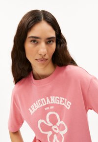 Roze katoenen T-shirt met een witte bloemenafbeelding en de tekst "ARMEDANGELS SINCE 2007" in een gebogen ontwerp; korte mouwen en ronde hals.
