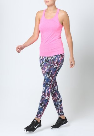 Débardeur de sport rose associé à des leggings à motifs comportant des couleurs bleue, violette et blanche, avec des chaussures de course noires.