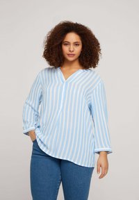 Blusa a rayas en azul claro y blanco con escote en V, mangas de tres cuartos y corte relajado. Confeccionada en tela ligera de textura suave.