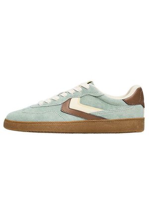 Baskets en daim bleu clair avec un accent en cuir marron. Elles présentent un logo blanc, des lacets beiges, une semelle en caoutchouc et des détails texturés sur la tige.