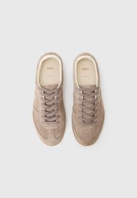 Sneakers in suede beige con punta arrotondata, superiore testurizzato e lacci tonali. Presentano una soletta beige chiaro con logo impresso.