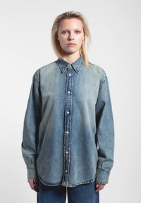 Denimshirt in een lichte tot middenblauwe verloopkleur, met knoopsluiting, puntkraag en lange mouwen met knoopmanchetten. Zachte textuur.