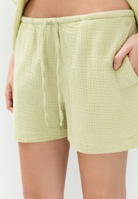 Ljust gröna, strukturerade bomullsbyxor med elastisk midja, dragsko och sidofickor. Har ett rutmönster överallt.
