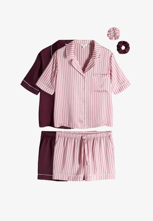 Twee sets korte mouw button-up pyjama’s met shorts; één in roze-witte strepen, de andere effen donkerpaars, met bijpassende scrunchies.