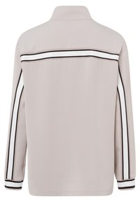 Helle beige Jacke mit Stehkragen, langen Ärmeln und schwarz-weißen Seitenstreifen. Glatte Textur, schlichtes Design und lockere Passform.