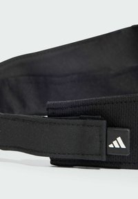 Un bandeau noir en tissu doux et texturé au design élégant. Présente un patch logo avec trois rayures. Ajustable avec une fermeture Velcro.