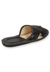 Black leather slide sandal featuring perforated upper design, curved shape, soft tan insole, and contrasting stitching details.