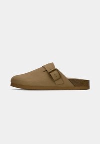 Light brown suede slip-on shoe with a thick sole and adjustable strap featuring a gold square buckle, shown from the side on white background.