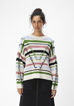 Suéter de punto multicolor con un patrón geométrico y acentos en verde, rosa y azul, y cuello redondo. Hilo grueso y texturizado.