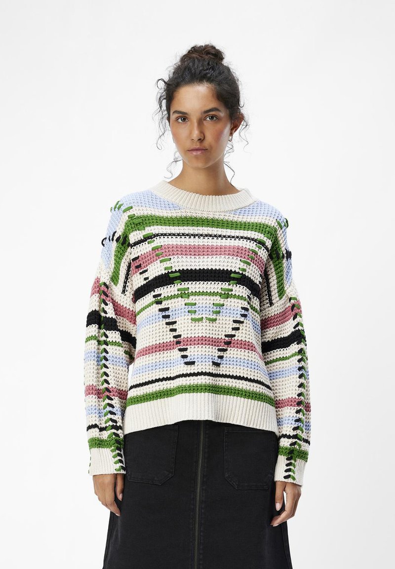 Suéter de punto multicolor con un patrón geométrico y acentos en verde, rosa y azul, y cuello redondo. Hilo grueso y texturizado.