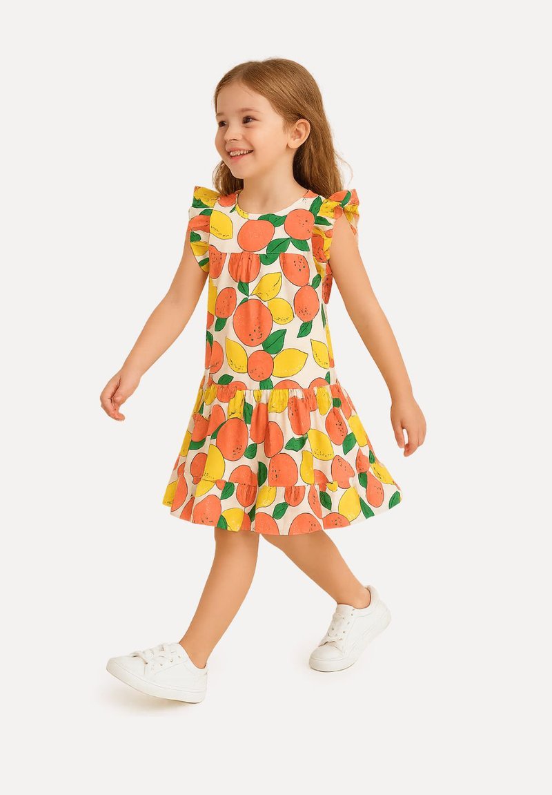 Gelbes Kleid mit orangefarbenen und zitronenartigen Mustern, mit Rüschensleeves und einem ausgestellten Rock, kombiniert mit weißen Sneakers.