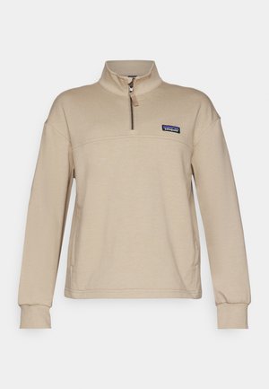 Beige fleece sweatshirt med halv lynlås, stående krave og lange ærmer. Har et lille patch-logo på venstre bryst. Blød tekstur.