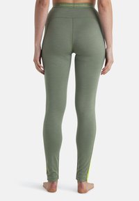 Olijfgroene leggings met een aansluitend ontwerp, gemaakt van zachte materialen. Kenmerkt zich door een brede tailleband en neongele accenten aan de zomen.