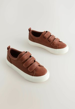 Baskets en toile brunes avec trois bandes Velcro, semelles en caoutchouc blanches et capuchon de pointe texturé. Boucle arrière pour un enfilage facile.