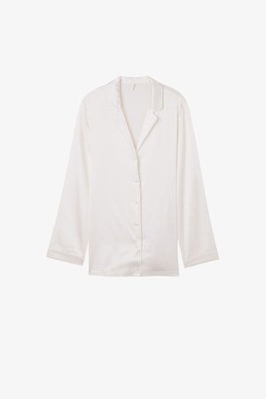 Chemise de pyjama en soie blanche avec un col cranté, des manches longues et une fermeture boutonnée sur le devant. Texture lisse et coupe décontractée.