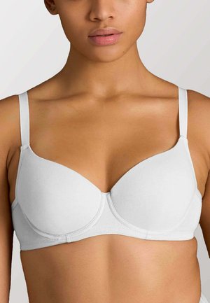 Donna che indossa un reggiseno bianco semplice con ferretto e spalline regolabili, mostrata dalle spalle fino a metà busto su sfondo neutro.