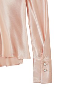 Helles rosa Satinbluse mit fließender Silhouette. Hat lange Ärmel und knopfbare Manschetten, die mit runden weißen Akzenten verziert sind.