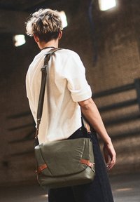 Borsa a tracolla verde oliva in pelle, con patta pieghevole, dettagli in pelle color cuoio, tracolla regolabile e logo in rilievo.