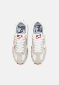 Baskets Levi's avec une tige en mesh blanc, des accents en daim gris, une semelle en caoutchouc gomme et des lacets blancs. Logo noir sur la languette.