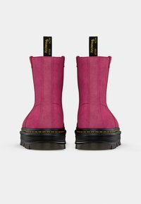 Bottines en daim fuchsia avec une semelle compensée noire épaisse, ornées de coutures jaunes et de languettes à l'arrière pour un enfilage facile.