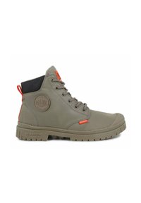 Bottes montantes en tissu khaki avec semelle en caoutchouc, bout arrondi, design à lacets, accents rouges sur le talon et le patch de la marque, surface texturée.