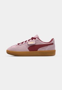 Baskets Puma Palermo en daim rose pâle avec des accents bordeaux, dotées d'une semelle en caoutchouc et d'un logo doré sur le côté.
