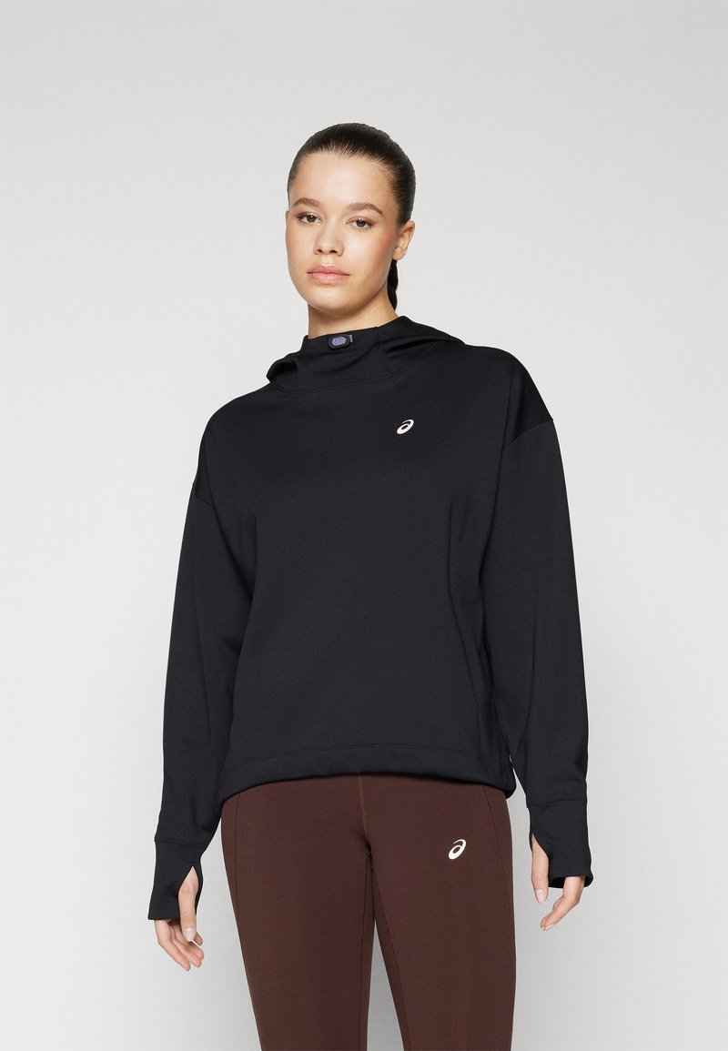 Black hoodie with a high neck, soft texture, and a small logo on the chest. Paired with dark brown leggings featuring a subtle logo.