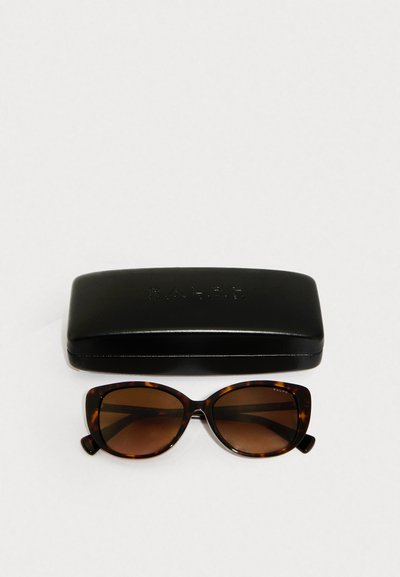 Occhiali da sole in tartaruga marrone con forma a occhio di gatto, dotati di lenti scure, presentati con un astuccio rigido nero impresso con "RALPH."
